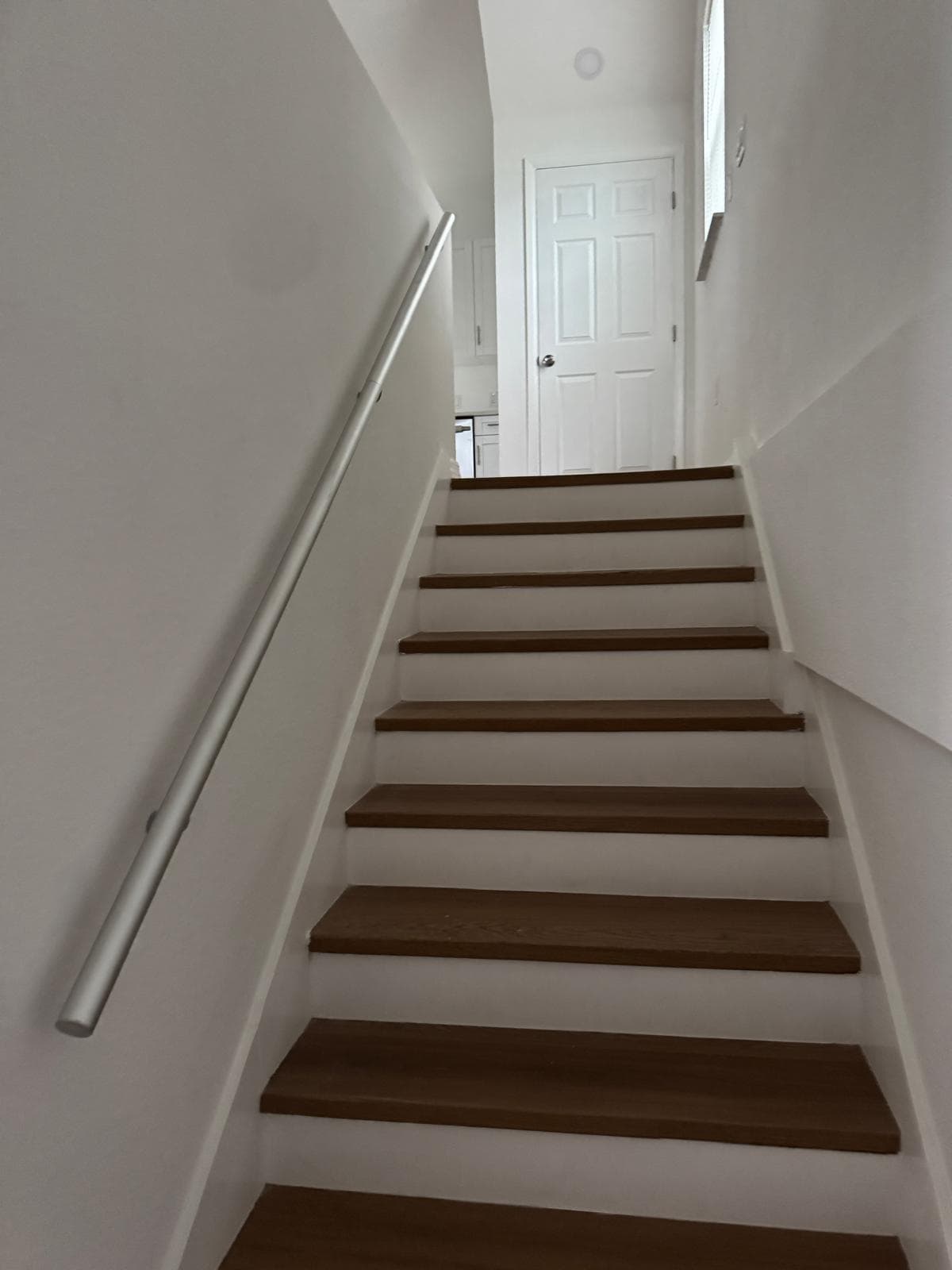 Clean hardwood stair treads with painted risers and modern metal handrail by Benito Fine Carpentry Wellington FL