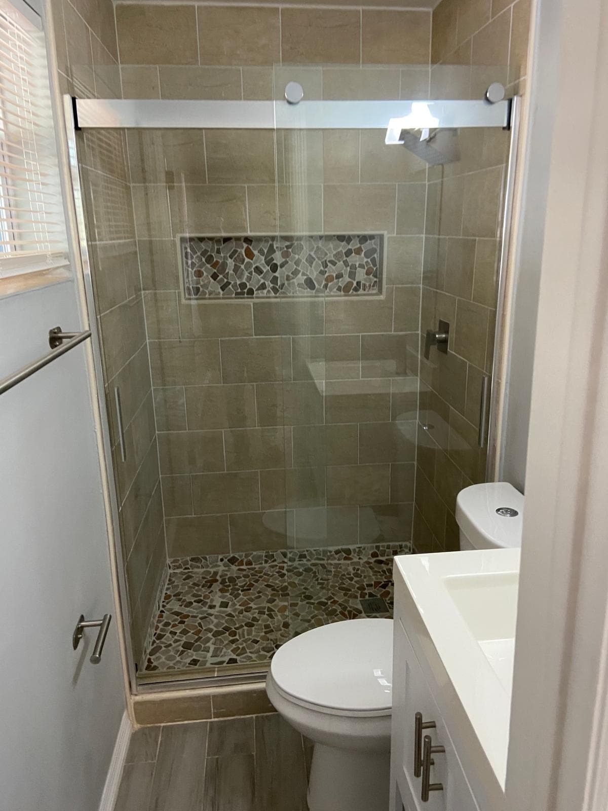 Pebble tile shower floor with frameless glass door bathroom remodel Wellington FL