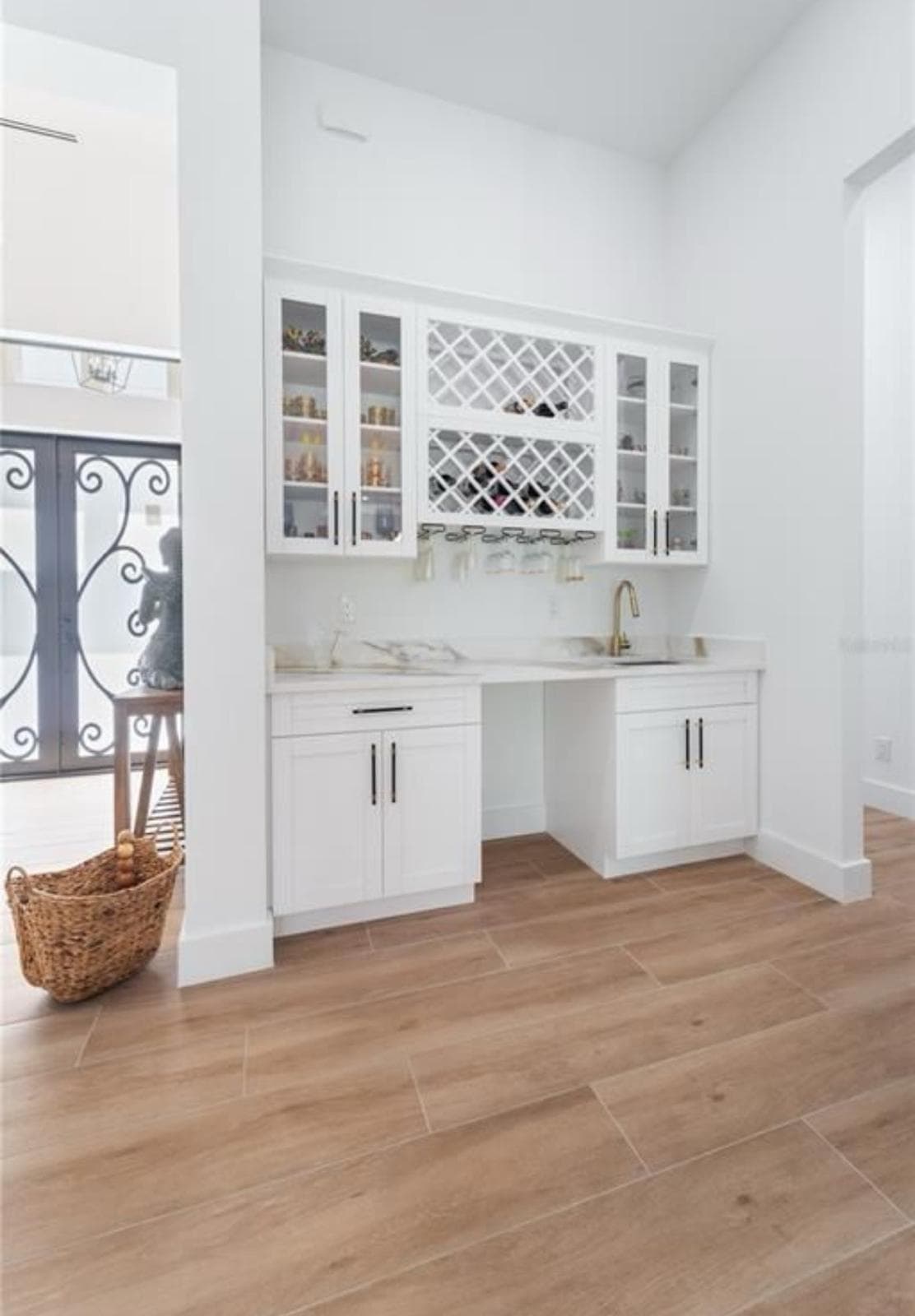 White wine rack built-in cabinet with brass faucet and glass-front doors by Benito Fine Carpentry Wellington