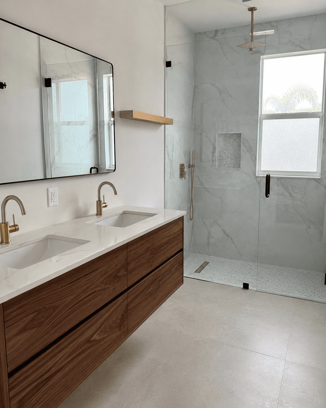 Floating walnut vanity brass faucets marble slab shower frameless glass custom bathroom remodel by Benito Fine Carpentry