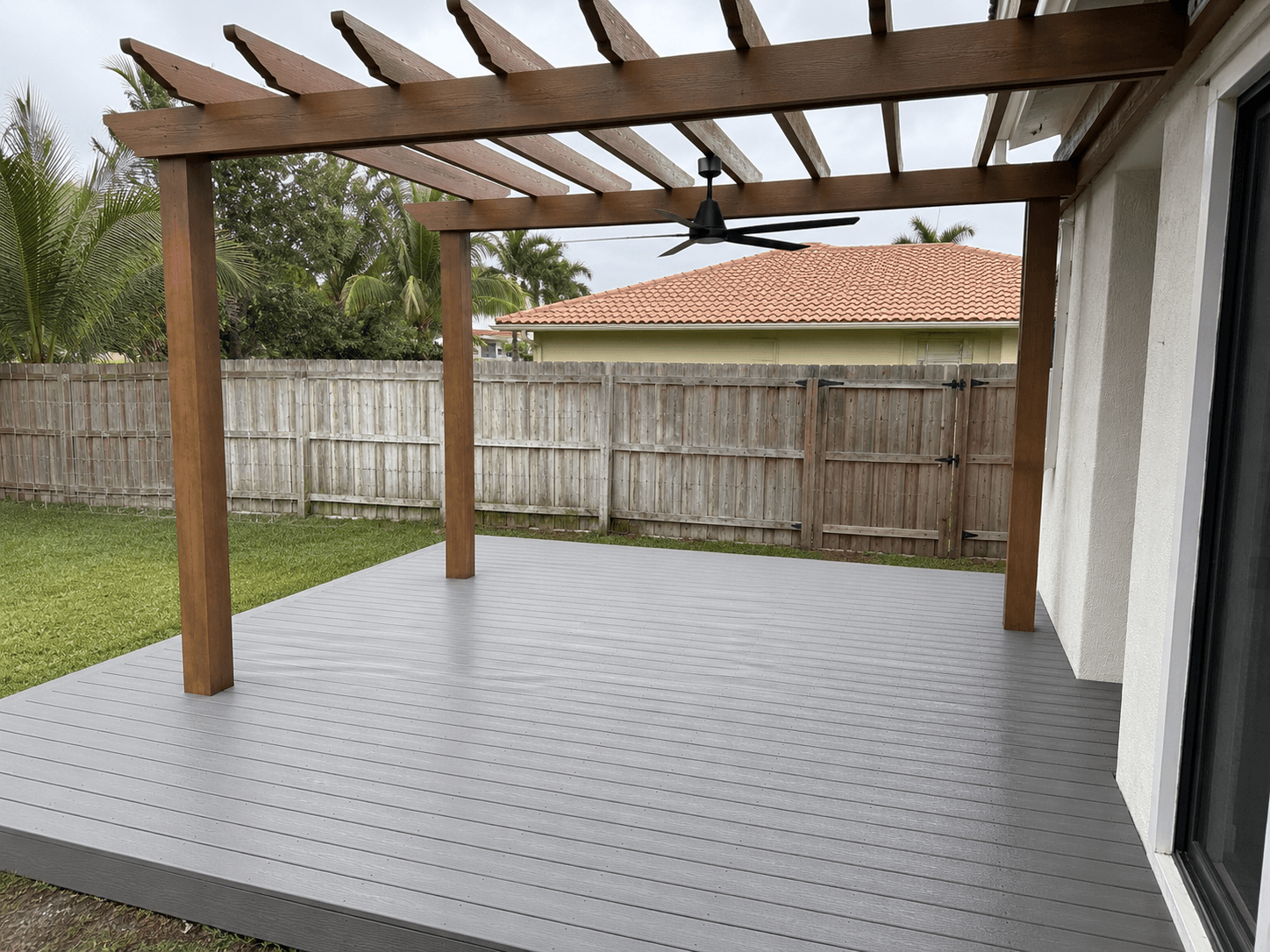 Gray Trex composite deck with stained cedar pergola and ceiling fan built by Benito Fine Carpentry Palm Beach County FL