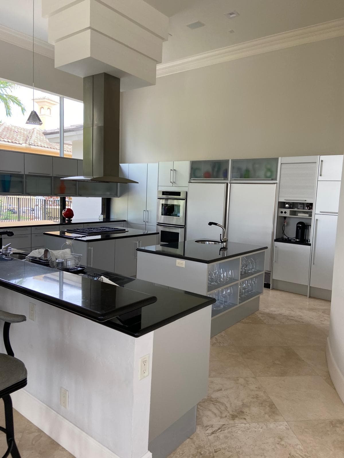 Modern high-end kitchen remodel with dark granite island, gray high-gloss cabinets and travertine floors by Benito Fine Carpentry Palm Beach