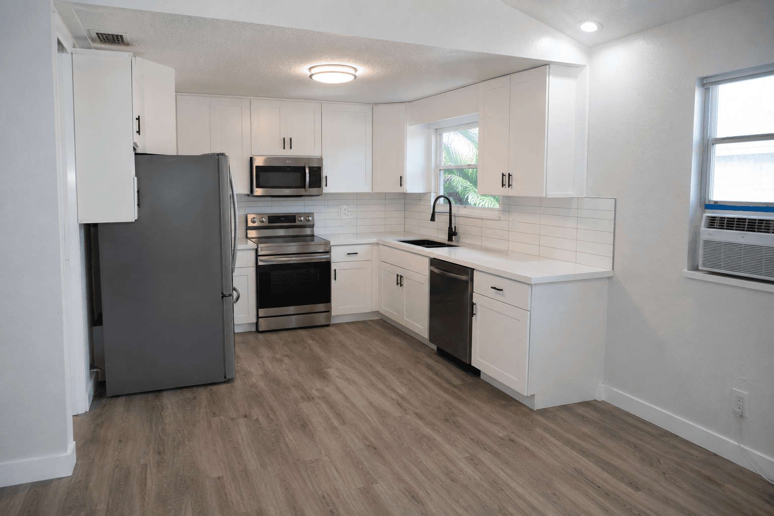 Complete kitchen renovation white cabinets vinyl plank floor stainless appliances South Florida by Benito Fine Carpentry