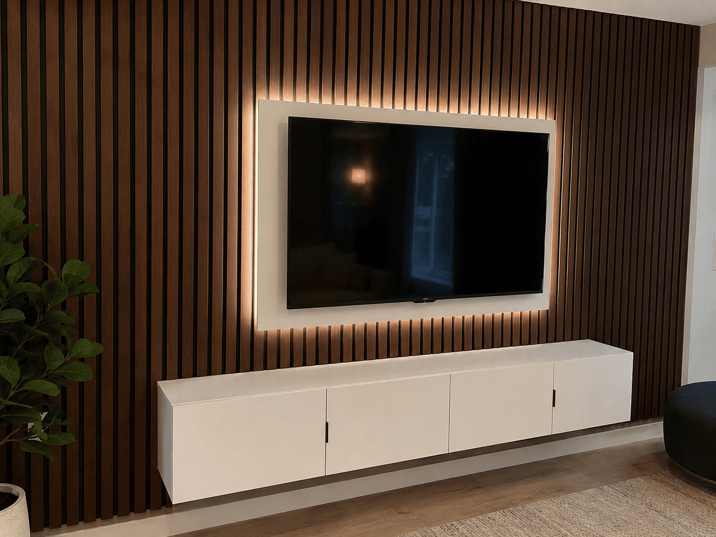 Dark wood slat accent wall with LED backlit TV and floating white media cabinet — custom woodwork by Benito Fine Carpentry Palm Beach County