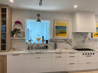 White kitchen sink area with window marble backsplash and clean cabinetry by Benito Fine Carpentry Wellington FL
